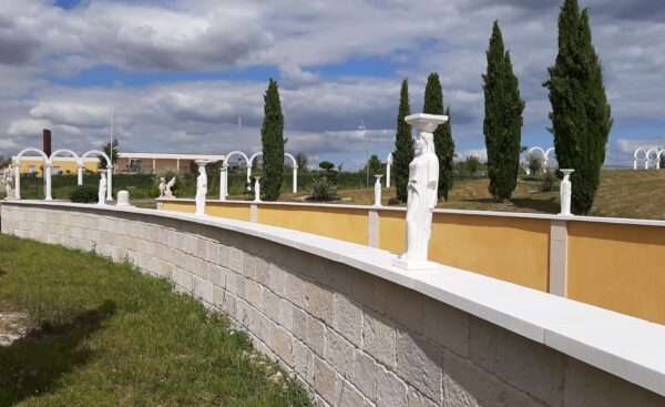 Mur de clôture revêtu des plaquettes de parement et des couvertines plates en pierre reconstituée