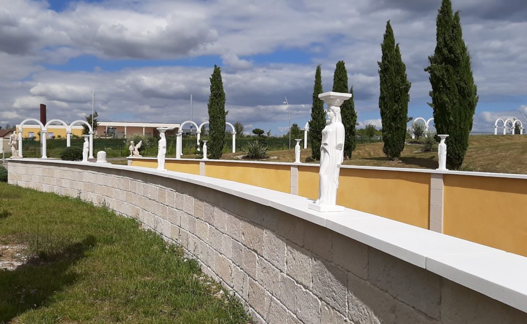 Mur de clôture revêtu des plaquettes de parement et des couvertines plates en pierre reconstituée.