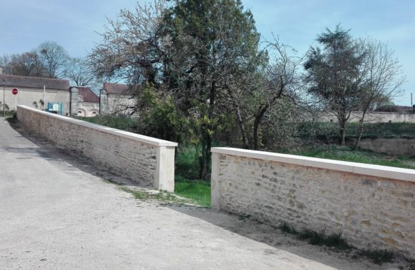 Couvre-murs (couvertines) en pierre reconstituée, aspect bouchardé-ciselé, visibles à Arcelot, 21310, en face du Château d'Arcelot (Bourgogne).